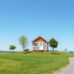 A picturesque landscape featuring a tiny house nestled on a small plot of land surrounded by nature